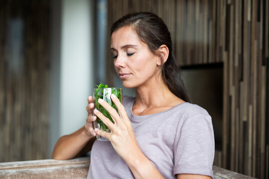 A relaxed woman smells infused mint water indoors