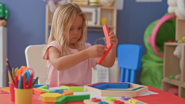 Girl placing wooden blocks into a hexagon puzzle frame on a playroom table; quiet concentration learning.