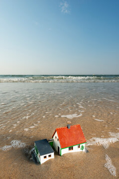 Model house at floodline on beach symbolizing climate change in the Netherlands