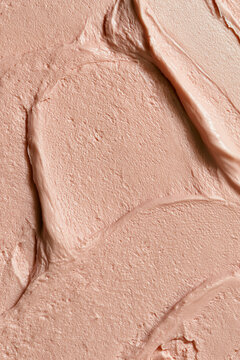 Pink cosmetic cream or facial mask close up with smeared strokes, creating a rich, smooth texture background for beauty products