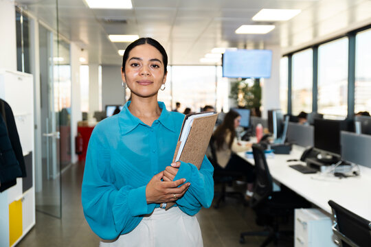 Confident businesswoman holds a folder in a modern office