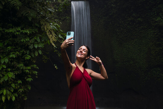 Smiling tourist takes a selfie near a jungle waterfall in Bali