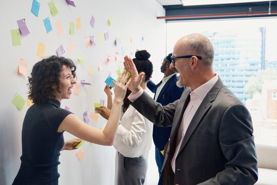 Businesswoman and businessman high five during an office meeting