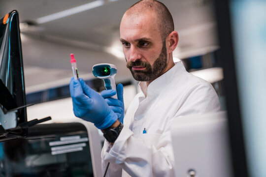 Male scientist scanning blood sample vial in laboratory