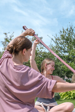 Female personal trainer assists woman with resistance band outdoors