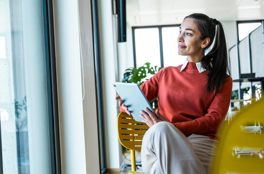 A friendly businesswoman holds a tablet in the office