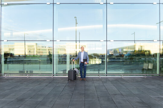 Confident businessman holds luggage outside Barcelona airport