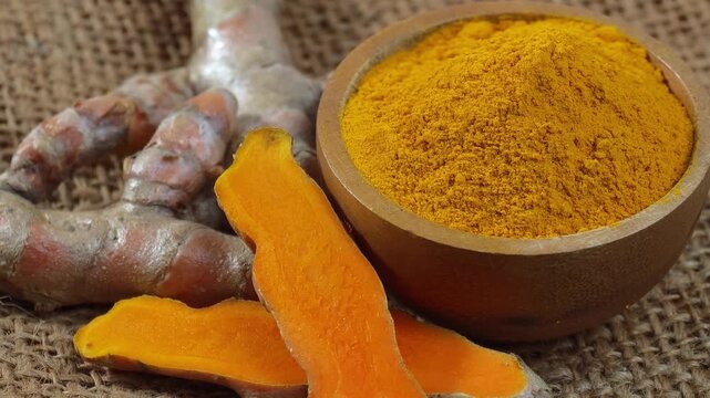 Fragrant turmeric powder in a spoon and a cup, and fresh turmeric root.