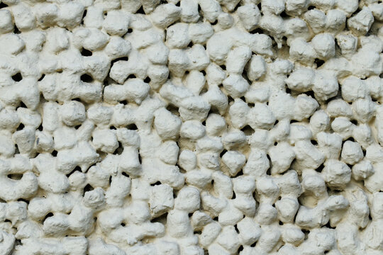 White, textured surface covered in irregular, porous rock fragments