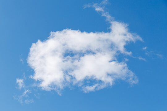 Soft white cloud drifts across bright blue sky