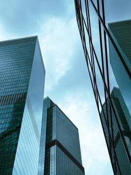 Glass skyscrapers rise against a cloudy sky