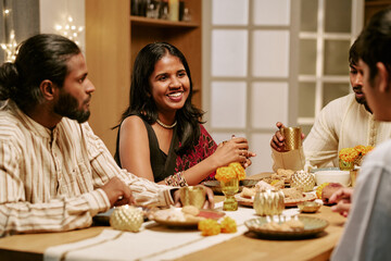 Obraz premium Indian young adults celebrating festival together while dining at festive table. Perfect for cultural event marketing, community building promotions, holiday campaigns