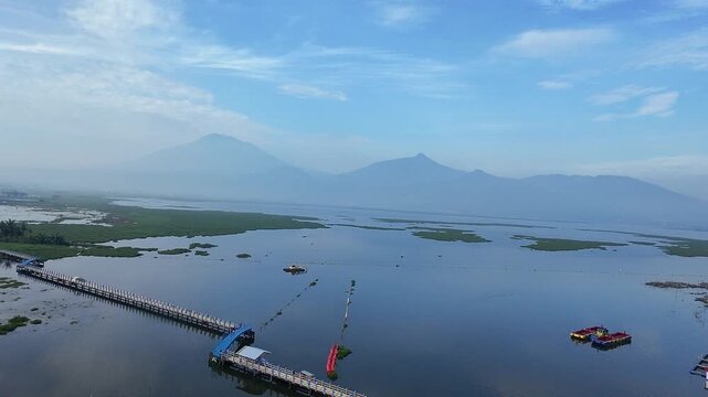 Beautiful aerial drone view of the Blue Bridge (Jembatan Biru Sumurup) at Rawa Pening lake with local village houses in Semarang, Central Java, Indonesia.
