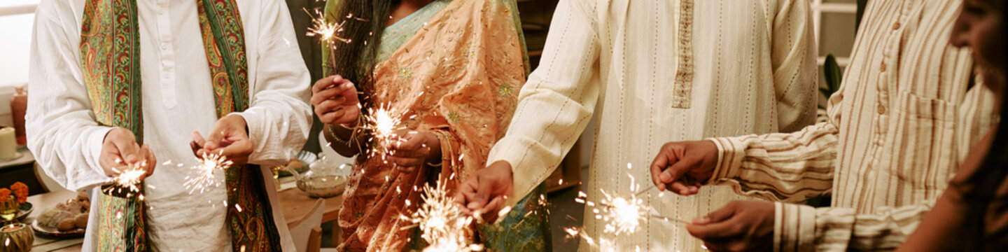 Header of Indian family holding sparkling sparklers during festival celebration together indoors. Scene suitable for holiday marketing campaigns and cultural event promotions