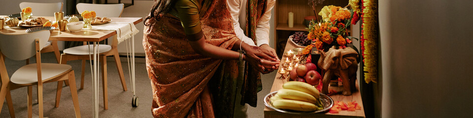Obraz premium Header of Indian young adult couple celebrating Diwali festival by lighting oil lamps together indoors. Image represents cultural tradition and holiday celebration for festive marketing campaigns