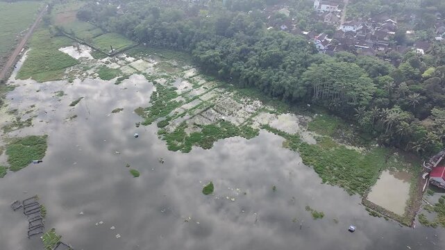 Beautiful aerial drone view of the Blue Bridge (Jembatan Biru Sumurup) at Rawa Pening lake with local village houses in Semarang, Central Java, Indonesia.