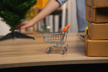 Miniature shopping cart next to stacked Christmas gift boxes for holiday sale concept © Oil And Den