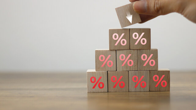 Show percentage icon on wooden blocks on coin stacks with down arrows, concept of interest rate adjustment, special offer, inflation, returns on investments, discount, tax, and financial management