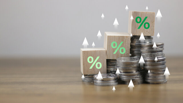 Show percentage of rising interest rates using wooden blocks with green percentage icons and coin stacks, representing financial growth, inflation control, investment returns, tax, and discount concep