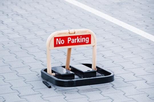 No parking barrier lock installed on paved lot surface blocking reserved space. Urban restriction concept.