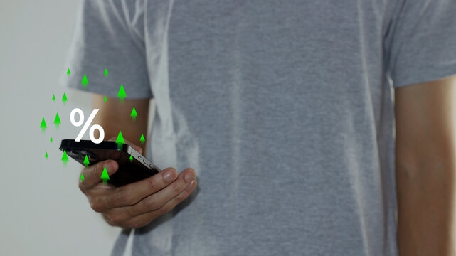 Show percentage icon and green rising arrows above a man holding smartphone for adjusting interest rates, raising interest rates to fight inflation, discount offer, tax concept, and finance returns