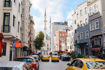 Street view in Istanbul showing a mosque and parked cars on a sunny day