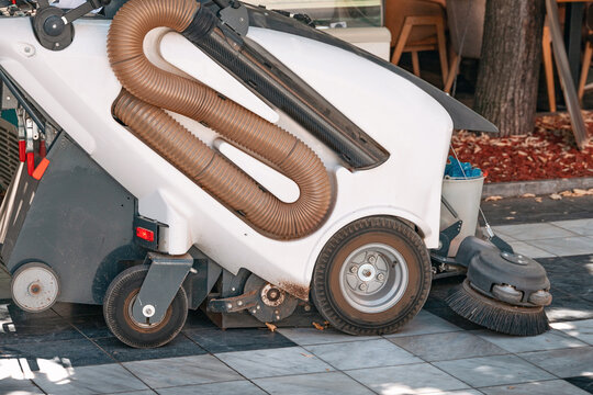 Industrial cleaning machine sweeping a public sidewalk, ensuring urban hygiene and maintaining neat city environments
