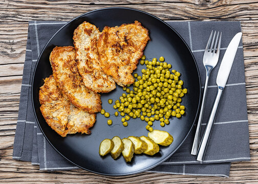Pork chops fried in batter on a plate with peas
