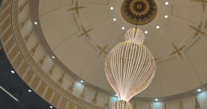 Ornate mosque dome interior with glowing spherical chandelier and golden Islamic patterns