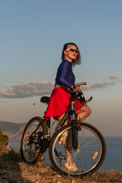 Bicycle, woman, mountain, young cyclist standing with mountain bike on cliff at sunset enjoying scenic nature view and freedom