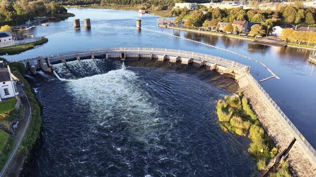 Aerial view of Salmon Weir on the River Corrib showing rushing water, weir gates, stone embankments and the surrounding Galway City waterfront.
