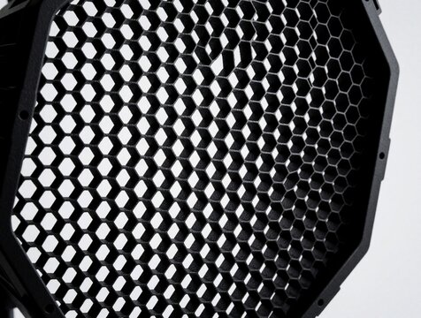 Black honeycomb grid light modifier for studio photography. Close up macro view of hexagonal pattern on pro lighting equipment. Geometric texture of dark plastic mesh used for controlling light beam