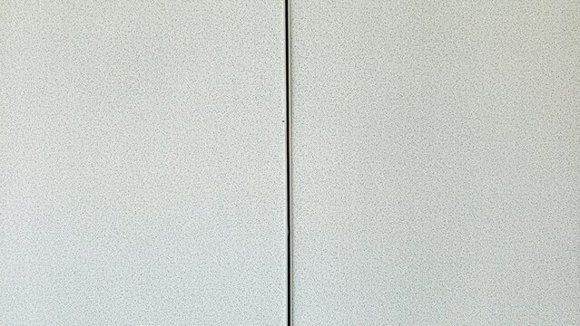 Textured background of a gypsum board partition wall featuring a single vertical dividing line in the center. Gypsum board used for constructing walls in modern homes.