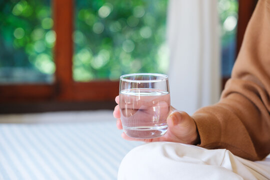 Closeup image of a woman holding a glass of drinking water