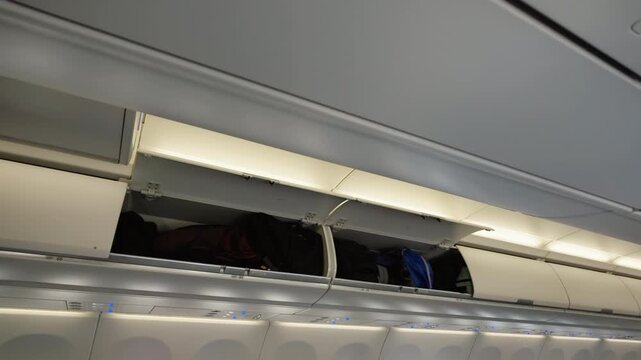 Passenger luggage in open airplane overhead compartment