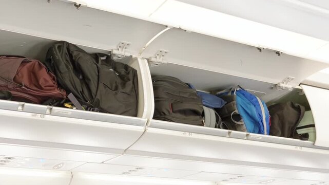 Open airplane overhead bin with carry-on luggage
