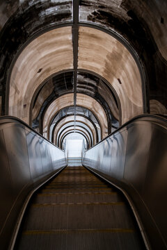 Escalator descends through a vaulted stone interior in Lyon France where arches symmetry and perspective create dramatic architecture and depth
