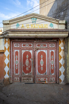 Carved wooden door with diamond pattern wall, Mandvi, India