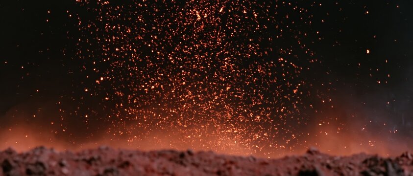 Glowing sparks and embers rising from a dark industrial surface at night