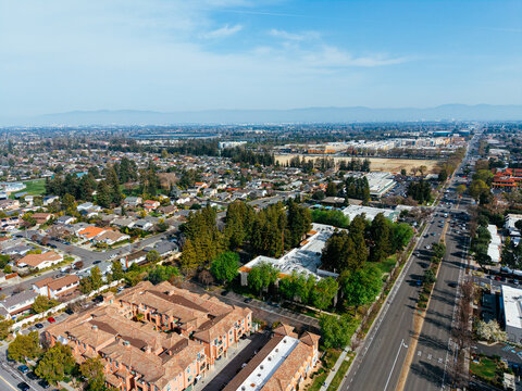 Aerial view of residential neighborhood in Cupertino, California with suburban homes and distant mountains. g.