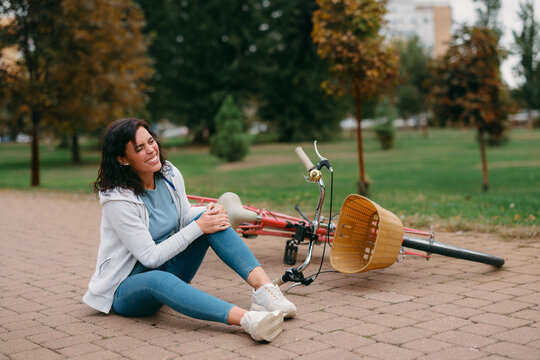Woman experiencing knee pain after falling off bicycle