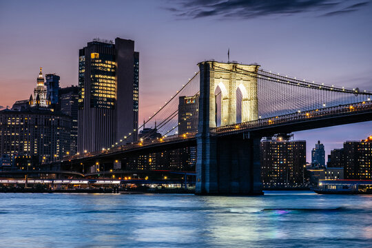 Brooklyn Bridge and Manhattan skyline at dusk over the East River in New York City, USA