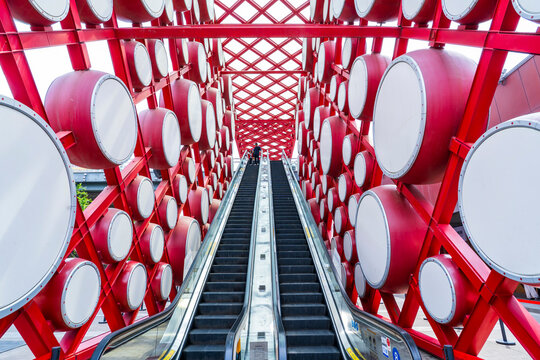 An outdoor escalator. On both sides are red drums.
