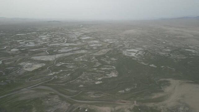 High altitude aerial view establishing shot of a majestic Mongolian steppe with river streams, yurts and grazing livestock, flat log profile