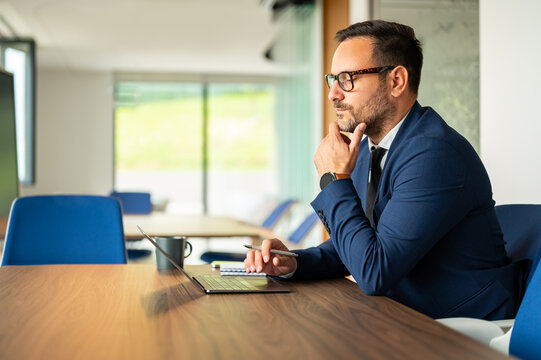 Professional businessman considering strategy in a modern office, planning solutions, and making important decisions at his computer workstation