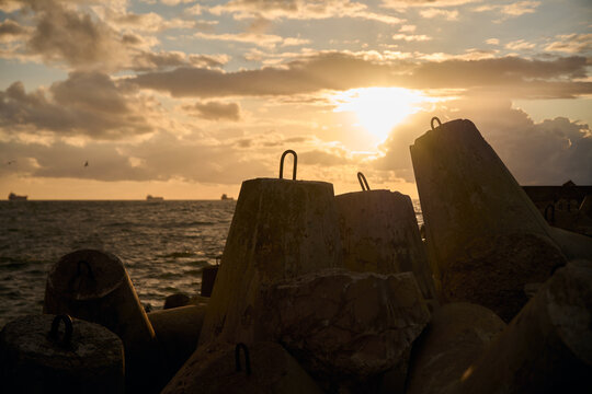Concrete wave breakers guarding shoreline beneath golden sunset light