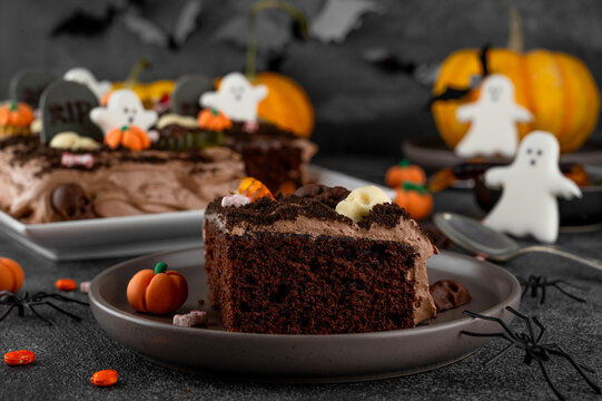Halloween chocolate cake. Dirty cake with chocolate cream, decorated with worms, skulls, ghosts, pumpkins and sugar sprinkles on a dark background.