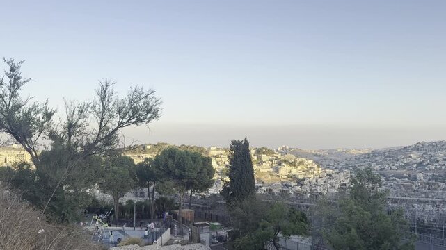 Jerusalem, Israel, 26 September 2026. Sunset view of Jerusalem&rsquo;s hills covered with houses, seen through the branches of a tamarisk tree.