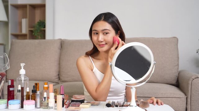 Asian beauty influencer recording makeup tutorial at home, skincare and cosmetics content creator livestream.