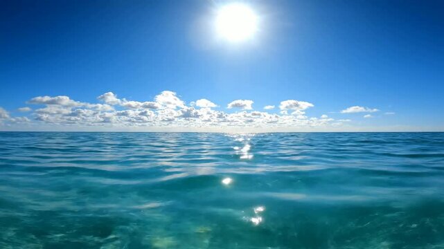 Crystal clear tropical ocean waves glinting under bright sun and blue sky with fluffy clouds tropical sea